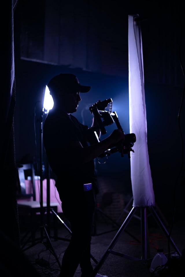 person in a dark room filming with camera